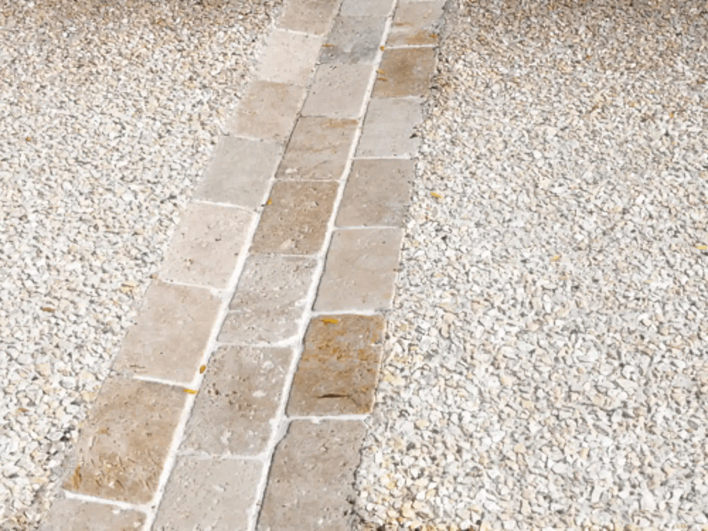 Detaliu de pavaj exterior care combină o alee din dale de piatră cu zone laterale din beton dezactivat (piatră spălată).