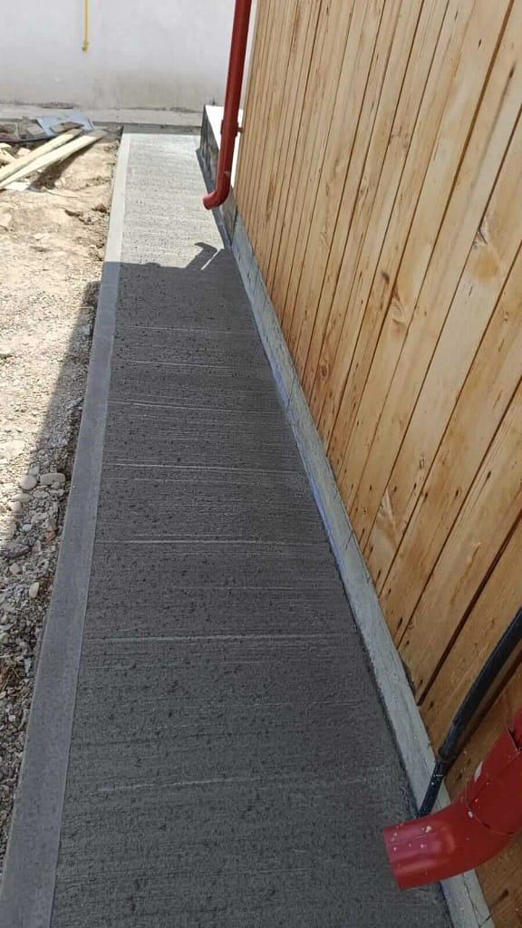 Alee îngustă din beton periat antiderapant executată lateral lângă casă